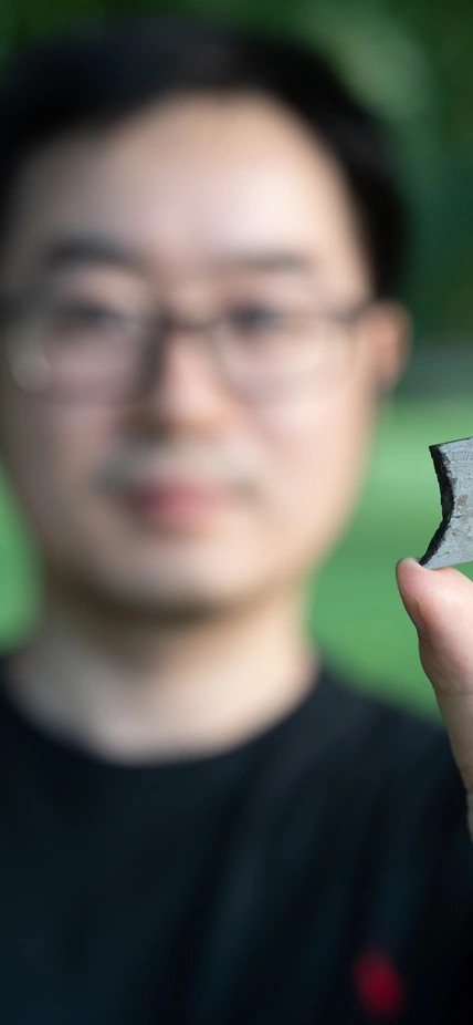 Peng Ni holds a piece of iron meteorite. Many iron meteorites are thought to be remnants of the cores of small planetary bodies in the early Solar System.
