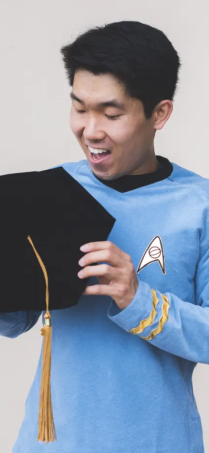 Mike Wong holds his PhD graduation cap in a Star Trek uniform