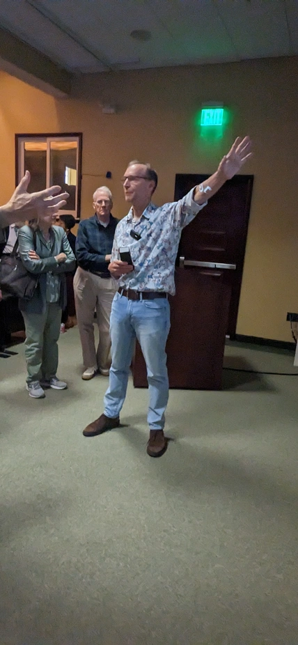Conel holds his hand up toward a meteorite sample during a discussion with neighborhood guests at the end of his Neighborhood Lecture