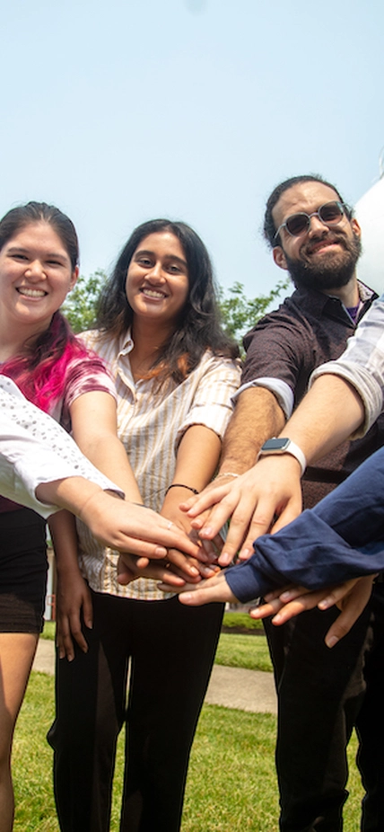 A group of interns puts their hands together. 
