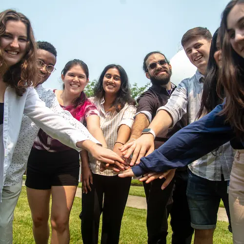 A group of interns puts their hands together. 