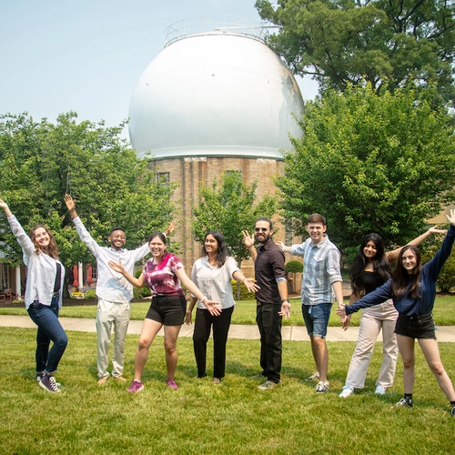 Interns cheer in front of the Atomic Physics Observatory